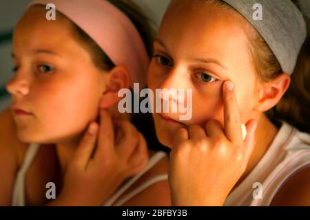 Zwei Mädchen überprüfen ihre Gesichter nach Flecken. Stockfoto
