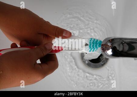 Zwei Mädchen waschen ihre Zahnbürsten unter fließendem Wasser Stockfoto