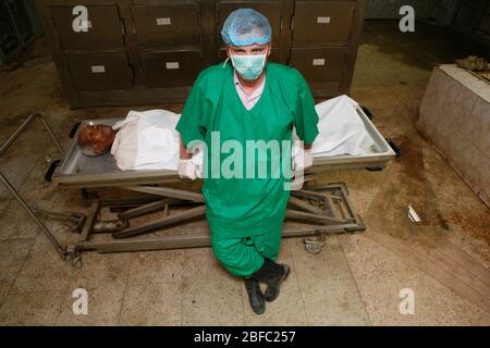Ein Pathologe steht über einer Leiche in einer Leichenhalle Stockfoto
