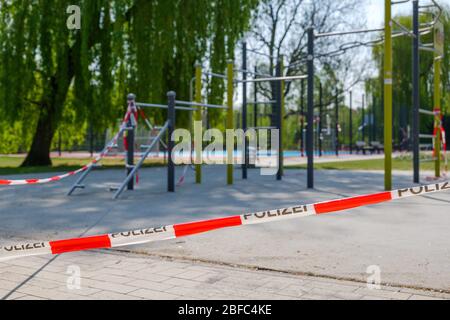Rot-weißes Warnband mit Text 'Polizei' bedeutet Polizei in deutscher Sprache, umhüllt von geschlossenen Spielzeugen im Freien während der sozialen Distanz. Stockfoto