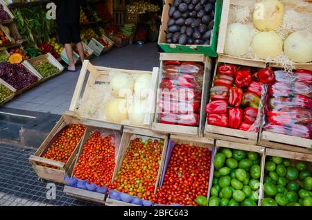 Straßenmarkt Verkäufer mit Lebensmitteln. Gemüse und Obst in Holzkisten draußen auf der Straße in der Nähe des Geschäfts. Rote Paprika, Kirschtomaten, Melone und cm Stockfoto