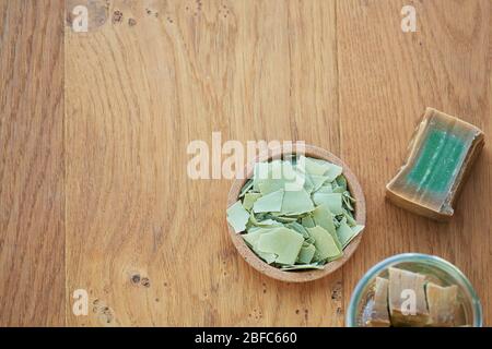 Flach lag oben Schuss einer Aleppo-Seife und Schnitte zeigen ihre grüne Farbe auf einem hölzernen Hintergrund. Konzept der Hygiene und Dermatologie, covid-19 und Stockfoto