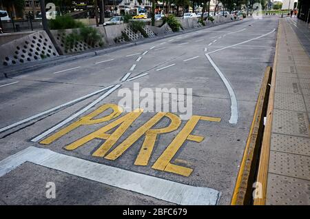 Gelbes Stoppschild auf Asphalt auf der Straße in der Nähe anderer weißer Verkehrslinien gemalt. Zeichen auf Spanisch bedeutet Stop. Buenos Aires, Argentinien. Stockfoto