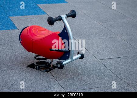 Rocker Spielzeug Reiter in einem öffentlichen Kinderspielplatz mit Gummi geflieste Matten Stockfoto