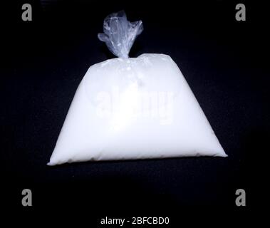 Milch in einer Plastikverpackung aus Polyethylen, gefährlich für die Gesundheit auf schwarzem Hintergrund - Bild Stockfoto