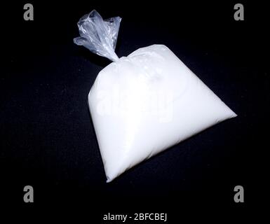 Milch in einer Plastikverpackung aus Polyethylen, gefährlich für die Gesundheit auf schwarzem Hintergrund - Bild Stockfoto