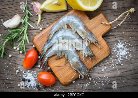 Frische Garnelen auf Holzschneidebrett mit Zutaten Kraut und Gewürzen zum Kochen von Meeresfrüchten/rohen Garnelen Stockfoto