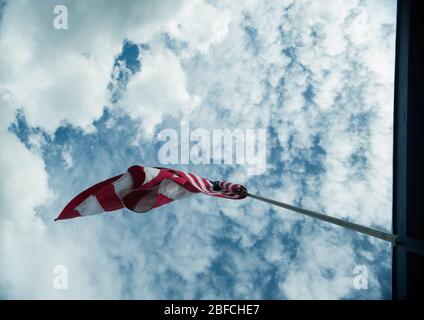 Amerikanische Flagge der USA weht im Wind hoch auf Fahnenmast hoch über dem Hintergrund des bewölkten blauen Himmel Symbol der amerika Sterne und Streifen Stockfoto
