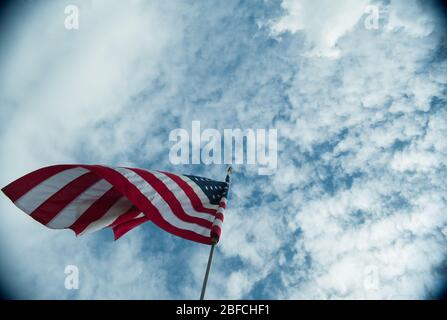 Amerikanische Flagge der USA weht im Wind hoch auf Fahnenmast hoch über dem Hintergrund des bewölkten blauen Himmel Symbol der amerika Sterne und Streifen Stockfoto
