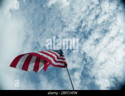 Amerikanische Flagge der USA weht im Wind hoch auf Fahnenmast hoch über dem Hintergrund des bewölkten blauen Himmel Symbol der amerika Sterne und Streifen Stockfoto