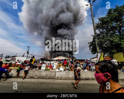 Capital District, Philippinen. April 2020. (Anmerkung für die Redaktion: Bild, das mit einem Mobilgerät aufgenommen wurde.) Evakuierte sahen hilflos entlang der Straße beobachten, wie Feuer durch "Happyland", ein Slum-Gebiet in Manila am Samstag, Barangay 105, Zone 9, Bezirk 1 und schnell ausgebreitet, was das Büro für Brandschutz, Task Force Alpha oder Mid-Level Alarm zu erhöhen. (Foto von Rick Mupas/Pacific Press) Quelle: Pacific Press Agency/Alamy Live News Stockfoto