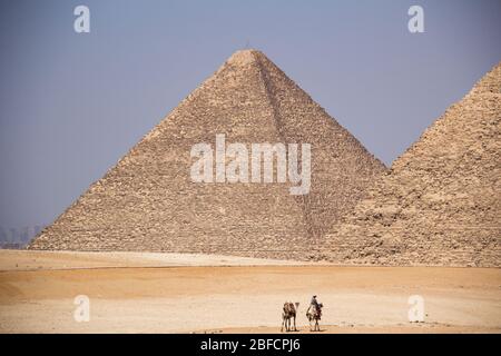 Ein Kamelreiter in der Wüste fährt vor der Pyramide von Khafre am Gizeh Pyramid Komplex in der Nähe von Kairo, Ägypten. Stockfoto
