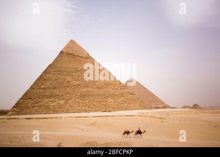 Ein Kamelreiter in der Wüste fährt vor der Pyramide von Khafre am Gizeh Pyramid Komplex in der Nähe von Kairo, Ägypten. Stockfoto