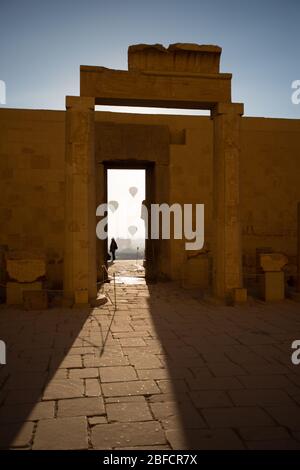 Heißluftballons, die über Luxor und der alten Stadt aufsteigen, wie vom Leichentempel der Hatschepsut am Westufer des Nils aus gesehen. Stockfoto