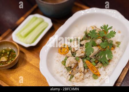 Nahaufnahme. Gebratener Reis mit Krabbenfleischplatte und Zwiebel, Knoblauch, Gurke, Zitrone, Ei und Suppenschüssel auf Holztisch. Thailändische Küche. Asiatische Küche. Draufsicht. Stockfoto