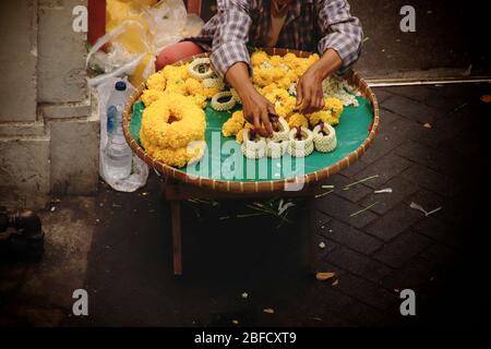 Thailändischer Straßenverkäufer, der Phuang malai oder malai verkauft, eine Blumengirlande, die für buddhistische Opfergaben und Glücksbringer in der thailändischen Kultur verwendet wird Stockfoto