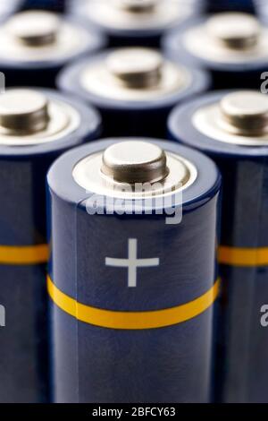 Batterien in Reihen. Nahaufnahme oder Makro von blauen AA Alkali-Batterien mit gelben Streifen und Pluszeichen auf dem Pluspol. Vertikales Bild. Stockfoto