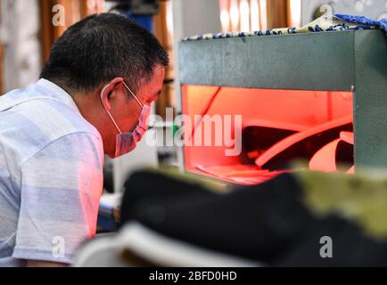(200418) -- CHENGDU, 18. April 2020 (Xinhua) -- EIN Arbeiter stellt handgefertigte Schuhe im Dorf Zhanqi der Gemeinde Tangchang in Chengdu, im Südwesten Chinas, in der Provinz Sichuan, am 17. April 2020 her. Lai Shufang, 62, ist seit über 40 Jahren in der Herstellung von handgefertigten Tangchang-Schuhen tätig. In der Gemeinde Tangchang ist Lais Familie die einzige, die noch Tangchang Tuchschuhe macht, die 32 Verfahren vor ihrer Fertigstellung enthalten. Wie viele Handwerker war Lai einmal besorgt, dass das Handwerk ausklingen würde und es keine Erben geben würde. Jedoch leitete das Handwerk in seiner Gelegenheit ein, zu gedeihen, wenn es Stockfoto