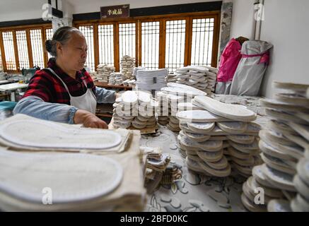 (200418) -- CHENGDU, 18. April 2020 (Xinhua) -- Lai Shufang arrangiert handgefertigte Schuhsohlen im Dorf Zhanqi der Gemeinde Tangchang in Chengdu, südwestlich der Provinz Sichuan, 17. April 2020. Lai Shufang, 62, ist seit über 40 Jahren in der Herstellung von handgefertigten Tangchang-Schuhen tätig. In der Gemeinde Tangchang ist Lais Familie die einzige, die noch Tangchang Tuchschuhe macht, die 32 Verfahren vor ihrer Fertigstellung enthalten. Wie viele Handwerker war Lai einmal besorgt, dass das Handwerk ausklingen würde und es keine Erben geben würde. Jedoch leitete das Handwerk in seiner Gelegenheit ein, zu Stockfoto