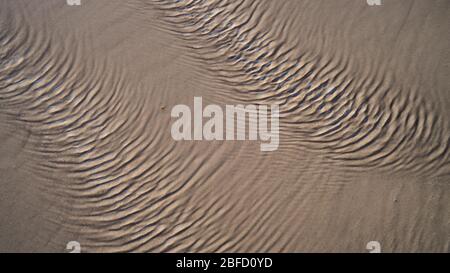 Eine Nahsicht der Wellen auf der Wasseroberfläche, die durch starken Wind im Sand am Strand erzeugt werden Stockfoto