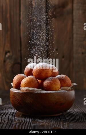 Donuts Kugeln mit Puderzucker bestreut auf einem Holztisch und rustikalen Hintergrund. Hausgemachtes Backen. Stockfoto