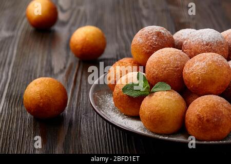 Hüttenkäse Donuts Kugeln mit Puderzucker bestreut auf einem Holztisch und rustikalen Hintergrund. Hausgemachtes Backen. Stockfoto