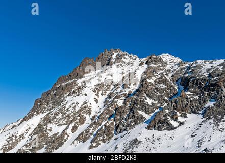 Zerklüftete alpine Felslandschaft am Berghang, bedeckt mit Schnee und Eis Stockfoto