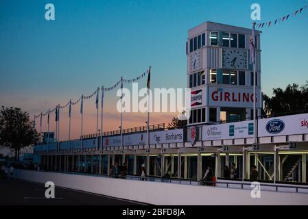 Goodwood Pit Lane bei Sonnenuntergang mit dem Rolex Girling Clock Tower, Goodwood Motor Racing Circuit bei Chichester, West Sussex, England Stockfoto