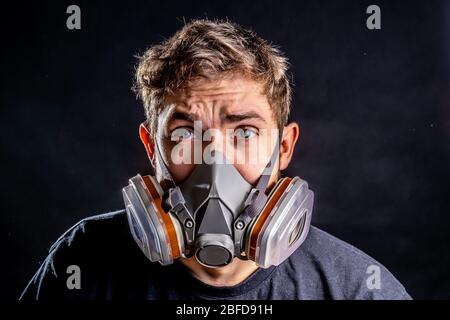 Ein Mann in einer Atemschutzmaske mit einem erhöhten Schutzgrad gegen schädliche Umweltfaktoren. Halbmaske. Isolieren Sie das Konzept der Virenangst. Stockfoto