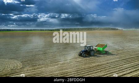 Traktoren arbeiten auf einem Feld, das den Boden für den Anbau von Kartoffeln anbaut. Luftaufnahme. Stockfoto