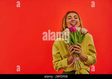 Schelmische Dame in einer gelben Bluse mit einem Bouquet von farbigen Tulpen. Stockfoto