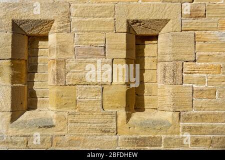 Details der schmalen, mit Steinen umrahmten Fenster, die in der Endwand der North Chapel auf dem Ilkley Cemetery in Yorkshire abgesperrt sind. Stockfoto