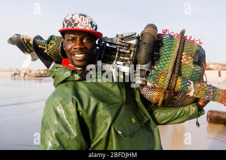 Porträt des Kapitän des Fischerboots Mohammed Sovv mit seinem Außenbordmotor nach einem Angeltag vor der Küste von Nouakchott, Mauretanien. Stockfoto