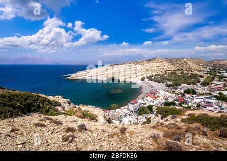 Die Küste und Berge von Matala an einem klaren Sommer sonnigen Tag mit Klippen im Vordergrund und einem bewölkten Himmel im Hintergrund. Kreta, Griechenland. Landschaft Stockfoto