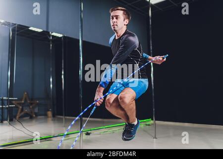 Muskulöser Mann Springseil. Porträt von muskulösen jungen Mann Training mit Seilspringen auf schwarzem Hintergrund Stockfoto