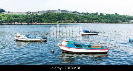 Havanna, Kuba - 25. Juli 2018: Drei kleine Fischerboote liegen vor der Melec Road mit dem El Morro Schloss im Hintergrund. Stockfoto