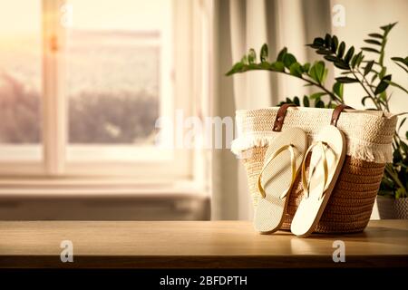 Holztisch mit Tasche und Kleidung und Kopierraum für Produkte. Schönes gemütliches und helles Zuhause. Hintergrund des Fensters mit natürlichem Licht. Stockfoto