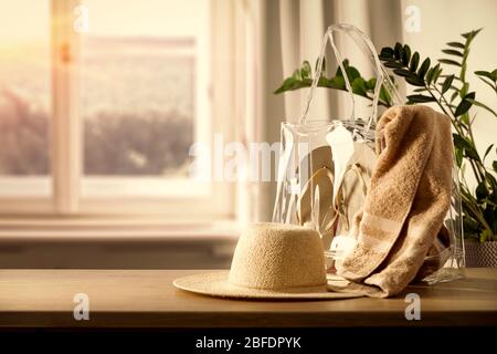 Holztisch mit Tasche und Kleidung und Kopierraum für Produkte. Schönes gemütliches und helles Zuhause. Hintergrund des Fensters mit natürlichem Licht. Stockfoto