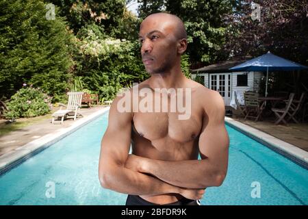 Ein junger sportlich aussehender Mann, der vor einem Schwimmbad steht. -Modell Freigegeben Stockfoto