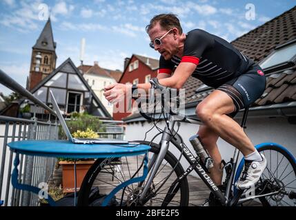 Herdecke, Deutschland. April 2020. Jan Postberg, Hobbyradfahrer, trainiert mit seinem Rennrad auf dem Balkon seines Nachbarn und schaut auf seinen Laptop, auf dem er mit mehreren hundert anderen Nutzern gleichzeitig auf einer virtuellen Trainingstrecke mit dem Simulationsprogramm Zwift fährt. Quelle: Bernd Thissen/dpa/Alamy Live News Stockfoto