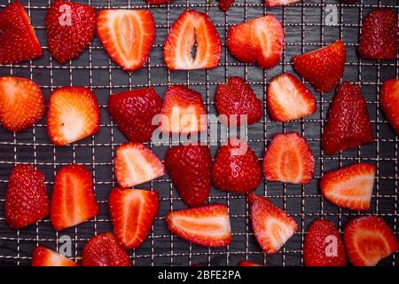 In Scheiben geschnittene reife Erdbeeren in Trockentabletts auf Holzhintergrund, frische Beeren Makro. Gesunde Snacks (Chips) , Mahlzeit, Draufsicht, Ansicht von oben Stockfoto