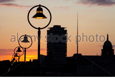 Lampen bilden ein schönes Stadtbild in Dublin, während die Sonne über der Hauptstadt versinkt. Im Hintergrund kann man die berühmte Turmspitze der O'Connell Street sehen. Stockfoto