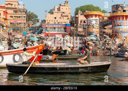 VARANASI, UTTAR PRADESH / INDIEN - APRIL 2019 : Boote, die im Ganges in der Nähe von Varanasi Ghats herumlaufen Stockfoto
