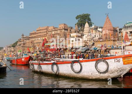 VARANASI, UTTAR PRADESH / INDIEN - APRIL 2019 : Boote, die im Ganges in der Nähe von Varanasi Ghats herumlaufen Stockfoto