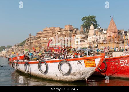 VARANASI, UTTAR PRADESH / INDIEN - APRIL 2019 : Boote, die im Ganges in der Nähe von Varanasi Ghats herumlaufen Stockfoto