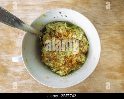 Draufsicht auf kleine Tasse mit handgefertigten Guacamole-Aufstrich gefüllt mit geriebenen und getrockneten Avocado-Stein gewürzt Stockfoto