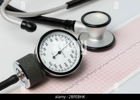 Nahaufnahme des Blutdruckmanschetten-Messgeräts, Stethoskops und EKG- oder EKG-Herzrhythmusstreifen. Konzept der Herzgesundheit, Bluthochdruck und Ernährung Stockfoto