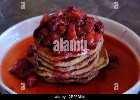 Stapel von veganen Pfannkuchen mit hausgemachter Erdbeersauce. Leckeres und gesundes hausgemachtes Frühstück. Stockfoto