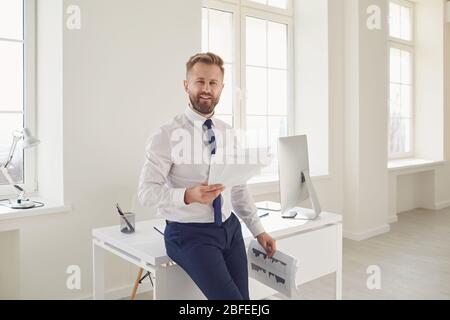 Blonder Geschäftsmann mit Papierdokumenten in den Händen, die im Büro arbeiten Stockfoto