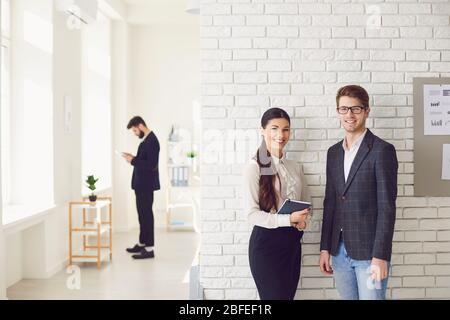Geschäftsleute stehen lächelnd Blick in einem weißen Büro. Stockfoto